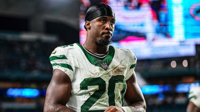 Jets running back Breece Hall walks off the field after a game, helmet in hand, jersey number 20 visible.
