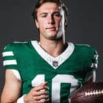 Cade Klubnik in a green New York Jets No. 10 uniform holding a football.