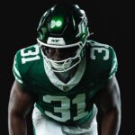 New York Jets player in a green uniform against a black background
