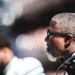 Aaron Glenn wearing sunglasses with a headset around his neck on the Jets sideline against Chicago.